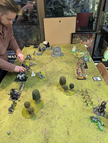 persoon die miniaturen verplaatst op een tafel met een oorlogsspel opstelling