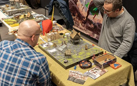 mensen die een tabletop spel spelen met miniaturen en terrein op tafel